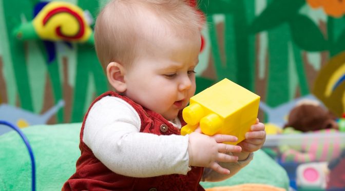 Baby playing with a yellow mega bloc